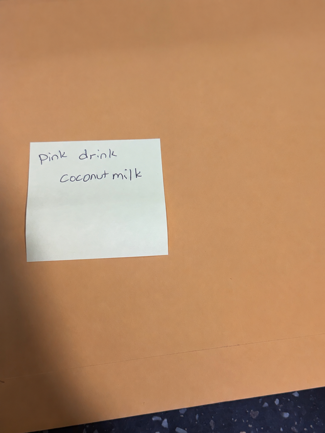 A handwritten Post-it note reading 'Pink Drink. Coconut milk.' — Anna's Starbucks order, written for the reporter at Moon Valley Justice Court.