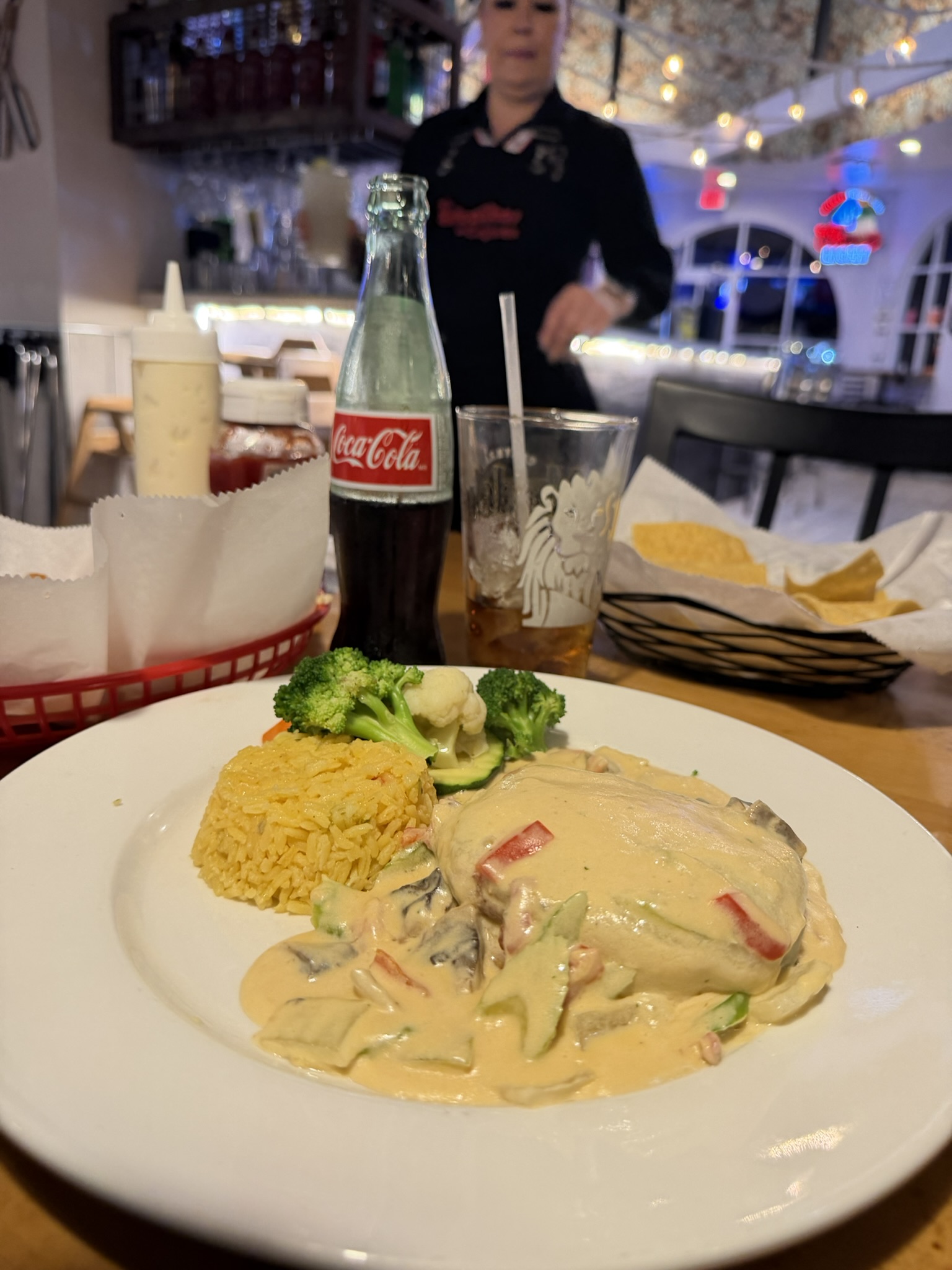 Camarón mignon: bacon-wrapped shrimp medallion topped with melted cheese and creamy mushroom sauce, served with yellow rice and vegetables