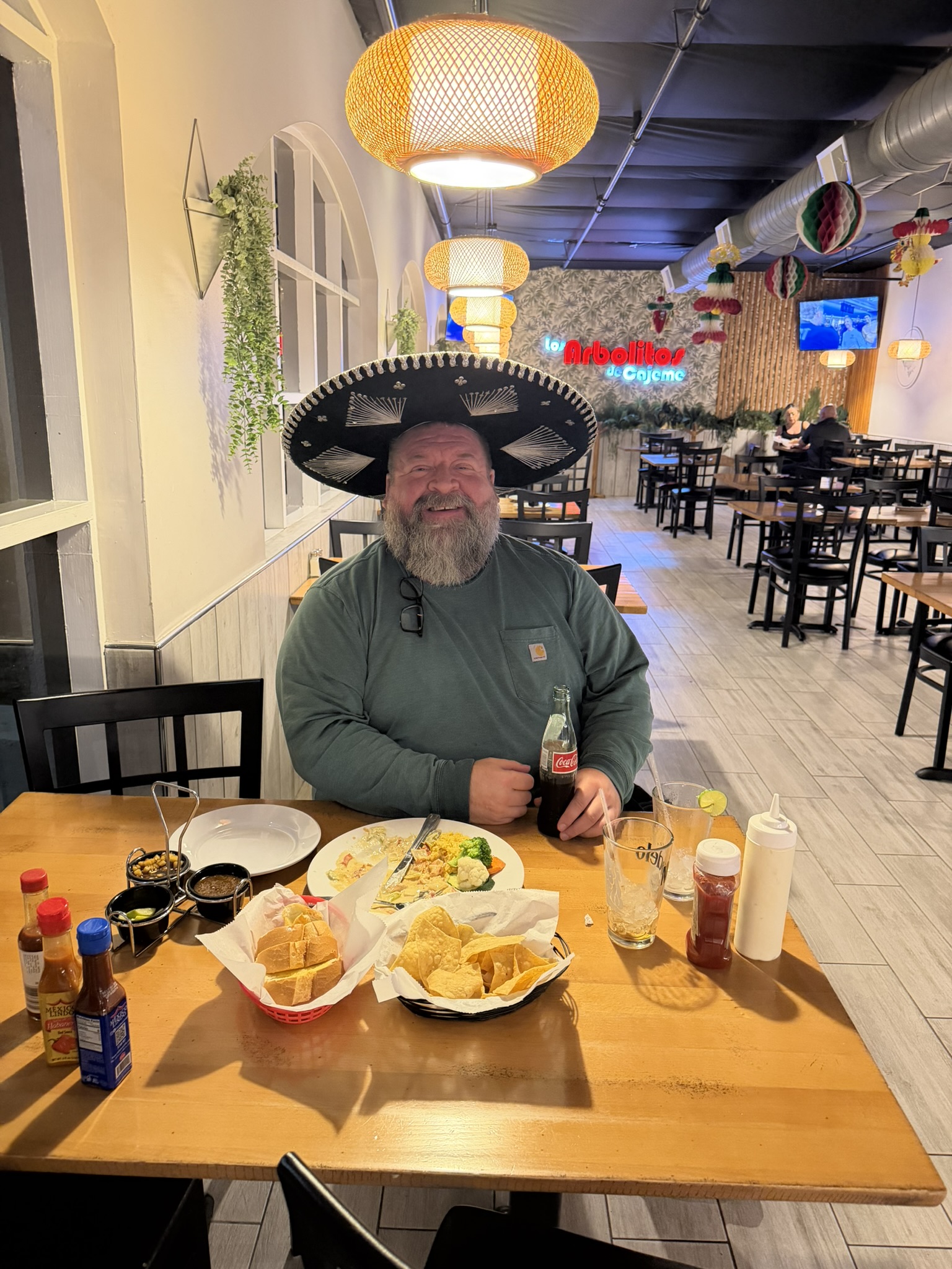 Andrew Edling wearing a black sombrero at Los Arbolitos de Cajeme, smiling while holding a bottle of Coca-Cola